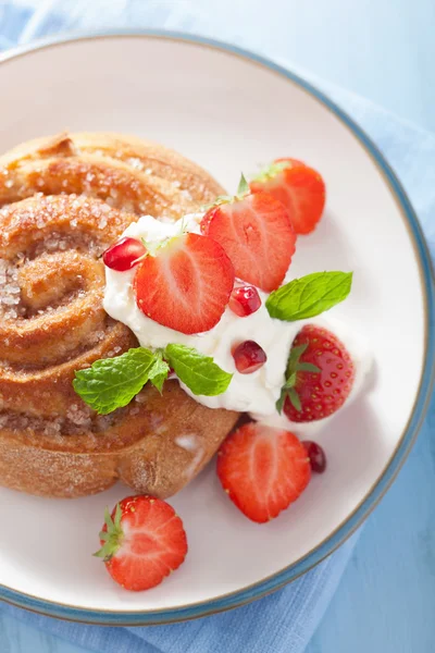 Söta kanelbulle med grädde och jordgubbar till frukost — Stockfoto