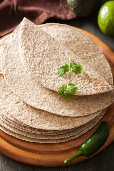 Tortilhas de trigo inteiras em tábua de madeira e legumes — Fotografia de Stock