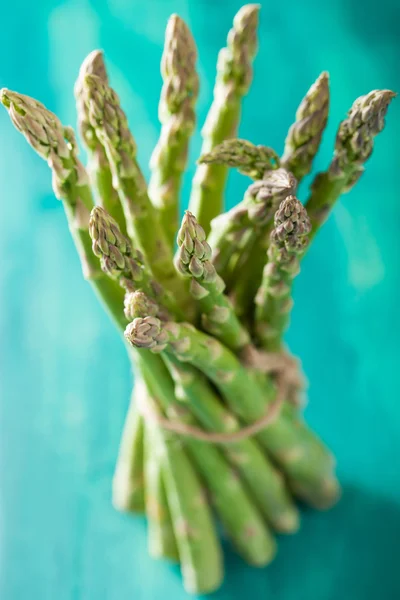 Bunch of fresh asparagus on turquoise background — Stock Photo, Image