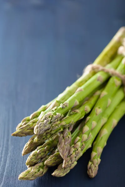 Bund frischer Spargel auf blauem Hintergrund — Stockfoto