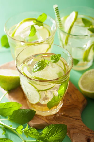 Frischer Mojito-Cocktail und Zutaten vor grünem Hintergrund — Stockfoto