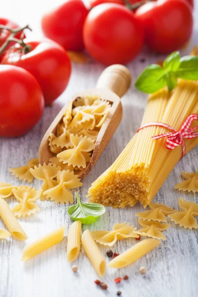 Pasta cruda spaghetti farfalle penne, pomodori. cucina italiana — Foto Stock