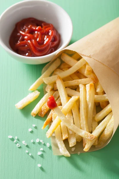 Batatas fritas com ketchup sobre fundo verde — Fotografia de Stock