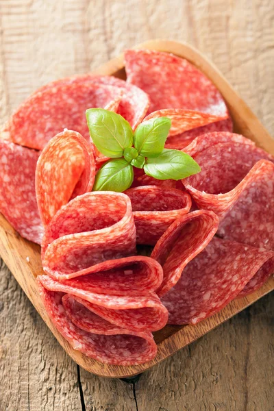 Salami slices in wooden plate — Stock Photo, Image