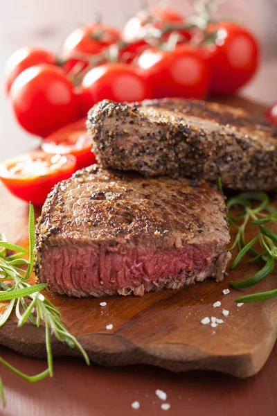 Hovězí steak s kořením a rozmarýnem na dřevěné pozadí — Stock fotografie
