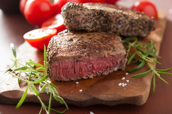 Hovězí steak s kořením a rozmarýnem na dřevěné pozadí — Stock fotografie