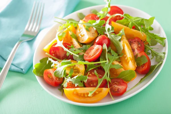 Tomato salad with arugula over green background — Stock Photo, Image