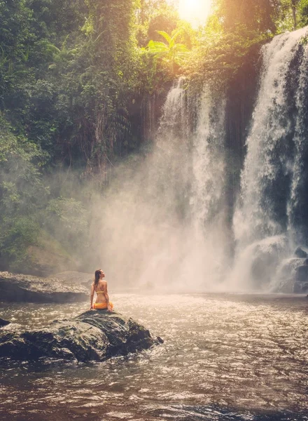 美丽的女人坐在靠近瀑布 — 图库照片