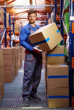 Porter carrying boxes in a warehouse  clipart
