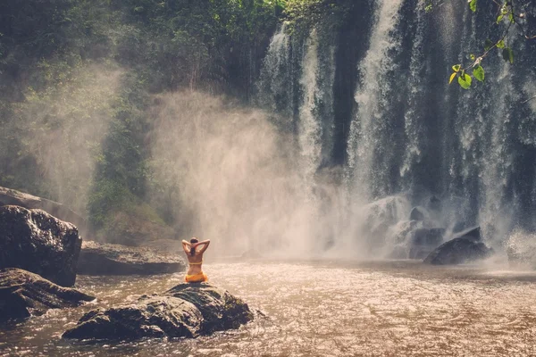 Beautiful woman sitting near waterfall — Stock Photo, Image