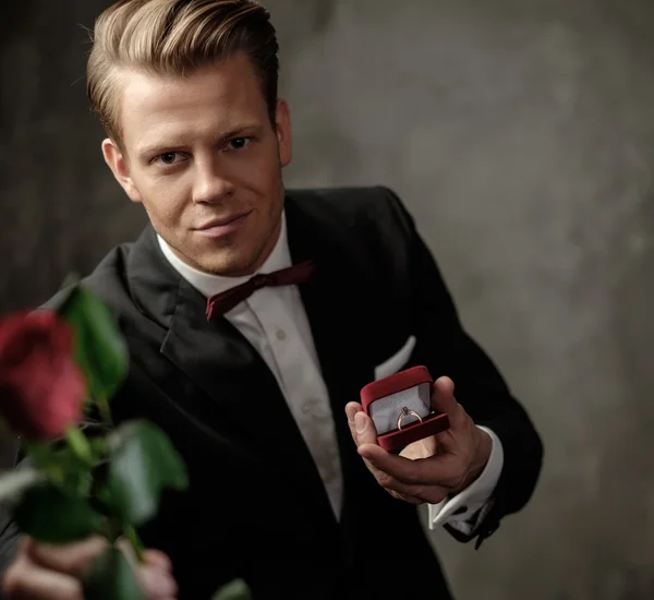 Человек держит коробку с кольцом предложения и красной розой — стоковое фото