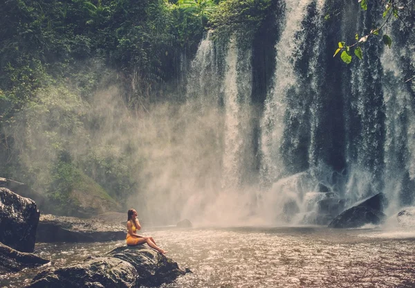 Bella donna seduta vicino alla cascata — Foto Stock