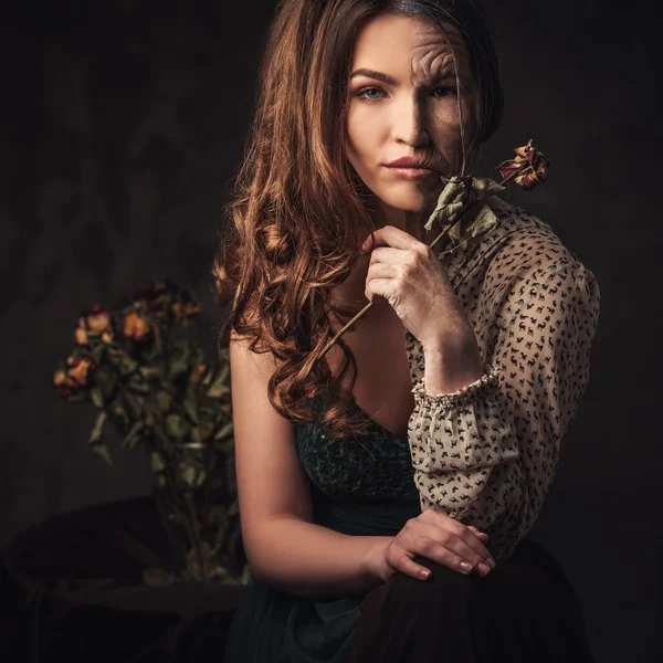 Aging and skin care concept. Half old half young woman with faded rose bouquet. — Stock Photo, Image