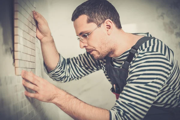 Construtor aplicando telha em uma parede — Fotografia de Stock