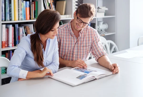 Fröhliches Ingenieurpaar, das Spaß beim Lesen eines Buches im Architekturbüro hat. — Stockfoto