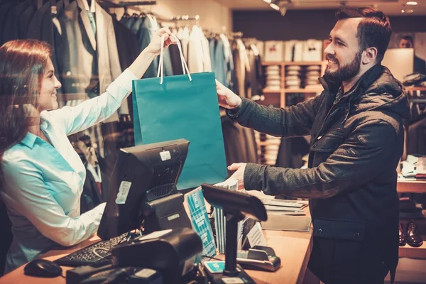 Gelukkig knap man nemen boodschappentas van verkoopster in een winkel pak. — Stockfoto