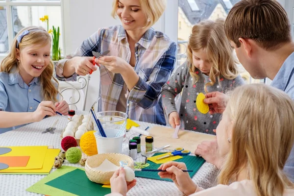 Familia que se divierte pintando y decorando huevos de Pascua . — Foto de Stock