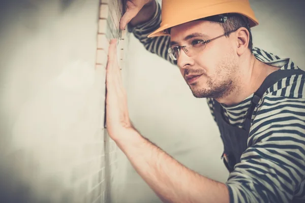 Construtor aplicando telha em uma parede — Fotografia de Stock