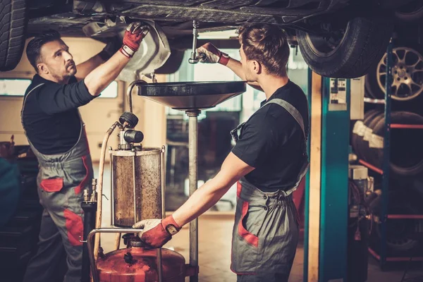 Kfz-Mechaniker wechseln Motoröl im Automotor bei Wartungsarbeiten in einer Kfz-Werkstatt. — Stockfoto