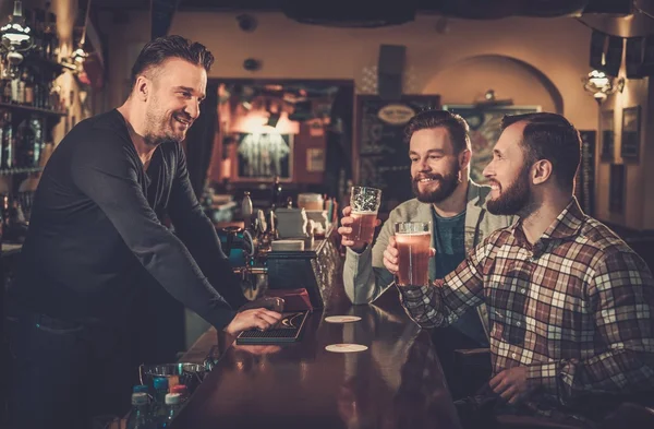 Amigos bebendo cerveja rascunho no bar balcão no pub . — Fotografia de Stock