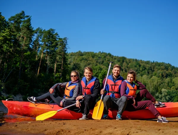 Grupp människor bär flytväst nära kajaker på en strand — Stockfoto