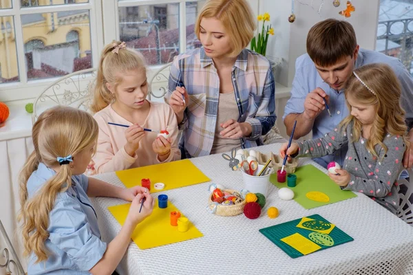 Familia que se divierte pintando y decorando huevos de Pascua . — Foto de Stock