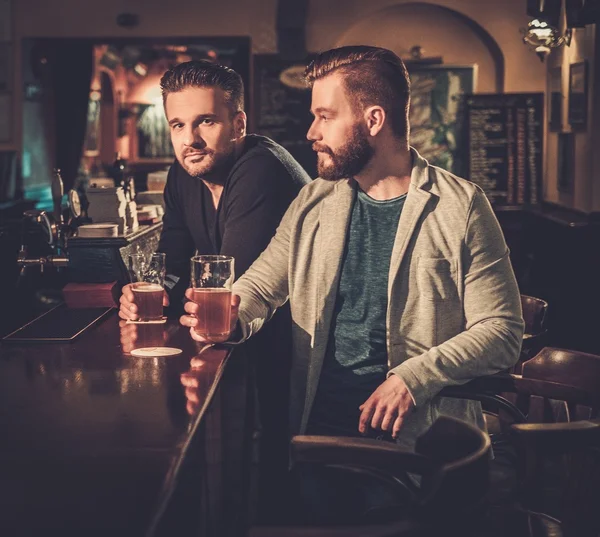 Friends drinking draft beer at bar counter in pub. — Stock Photo, Image