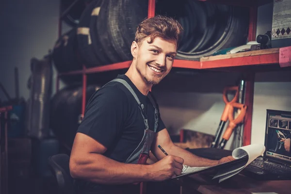 Mecánico de coche profesional en su lugar de trabajo preparando lista de verificación en el servicio de reparación de automóviles . — Foto de Stock
