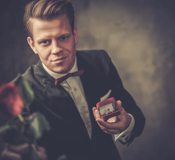 Homme tenant boîte avec une bague de demande en mariage et rose rouge — Photo