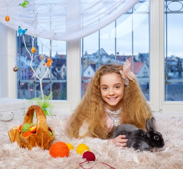 Hermosa niña acostada en la alfombra y jugando con conejito lindo . — Foto de Stock