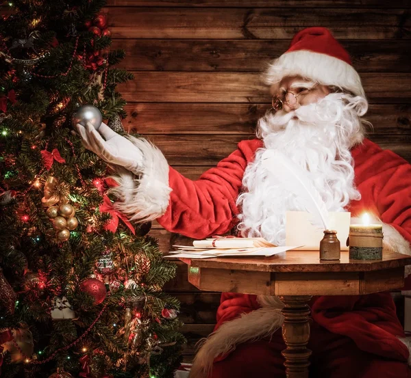 Santa claus in houten huis interieur kijken gedecoreerde kerstboom — Stockfoto