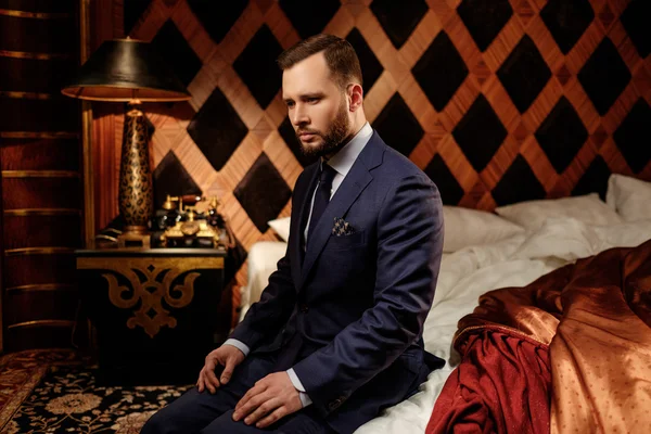 Confident well-dressed man in luxury bedroom interior. — Stock Photo, Image