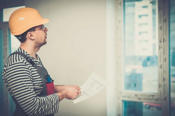 Contremaître avec plan de construction dans l'intérieur du nouveau bâtiment — Photo