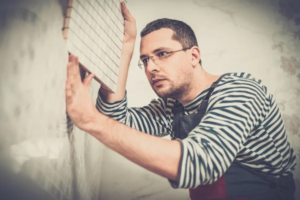 Constructor aplicando baldosas en una pared — Foto de Stock