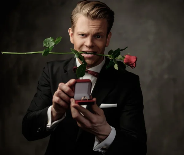 Homme tenant boîte avec une bague de demande en mariage et rose rouge — Photo