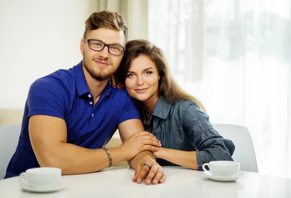 Pareja alegre detrás de la mesa en casa —  Fotos de Stock