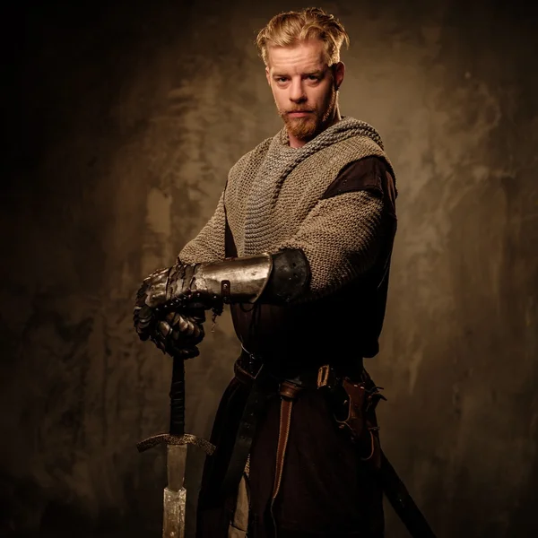 Young medieval knight posing on dark background. — Stock Photo, Image