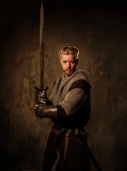 Young medieval knight posing on dark background. — Stock Photo, Image