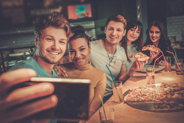 Multiracial vänner ha roligt äta pizza på pizzeria. — Stockfoto