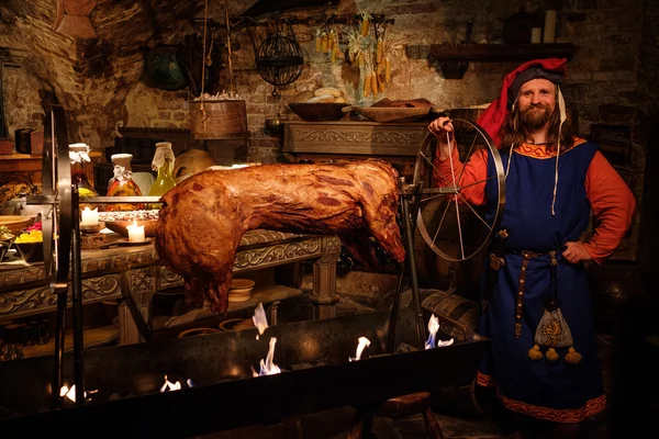 Homem medieval fazendo porco assado — Fotografia de Stock