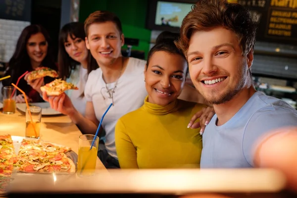 Multirassische Freunde haben Spaß beim Pizza essen in der Pizzeria. — Stockfoto