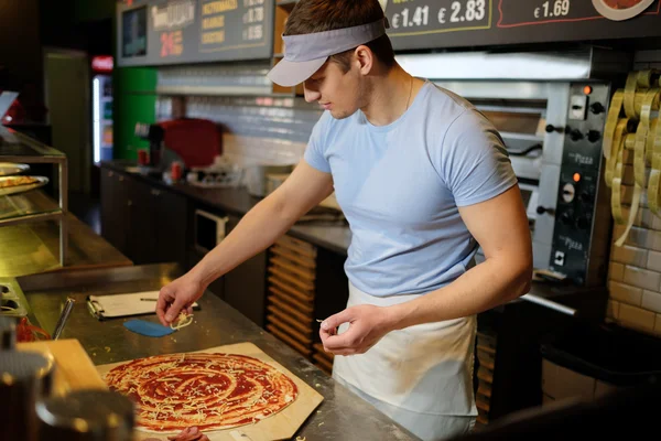 Pizzaiolo haciendo pizza en la cocina en la pizzería . —  Fotos de Stock