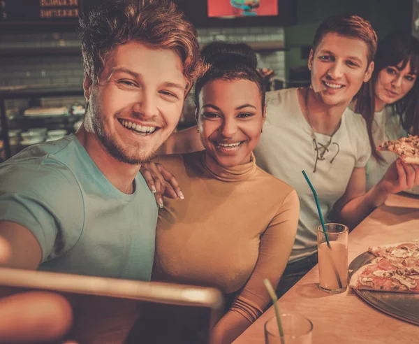 Multiracial vänner ha roligt äta pizza på pizzeria. — Stockfoto