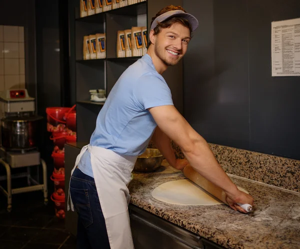 Knappe pizzaiolo rollend deeg met rolling-pin. — Stockfoto