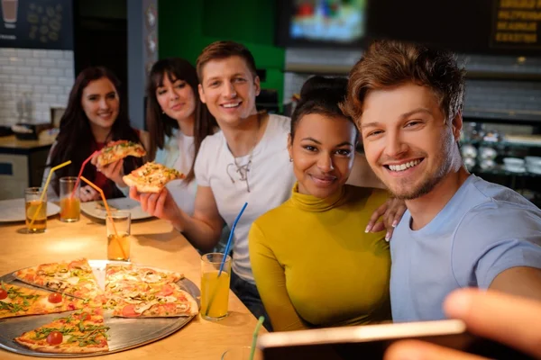 Mnohonárodnostní přátel bavit jíst pizzu v pizzerii. — Stock fotografie