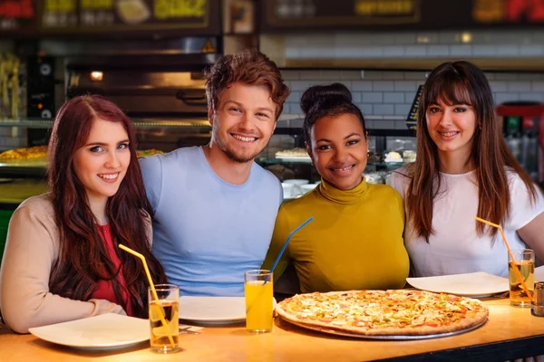 Mnohonárodnostní přátel bavit jíst pizzu v pizzerii. — Stock fotografie