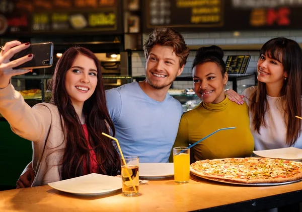 Багаторасові друзі весело їдять піцу в піцерії . — стокове фото