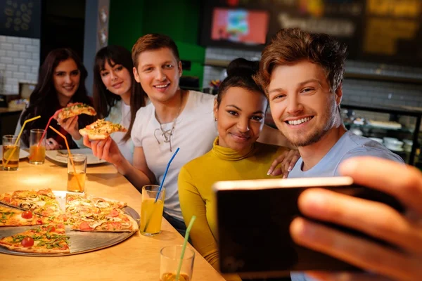 Amigos multirraciales divirtiéndose comiendo pizza en la pizzería . — Foto de Stock