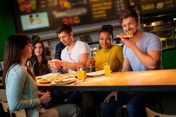 Multiracial vänner ha roligt äta pizza på pizzeria. — Stockfoto