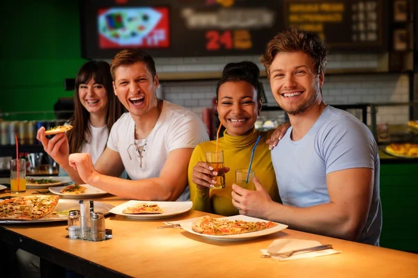 Multiracial vänner ha roligt äta pizza på pizzeria. — Stockfoto